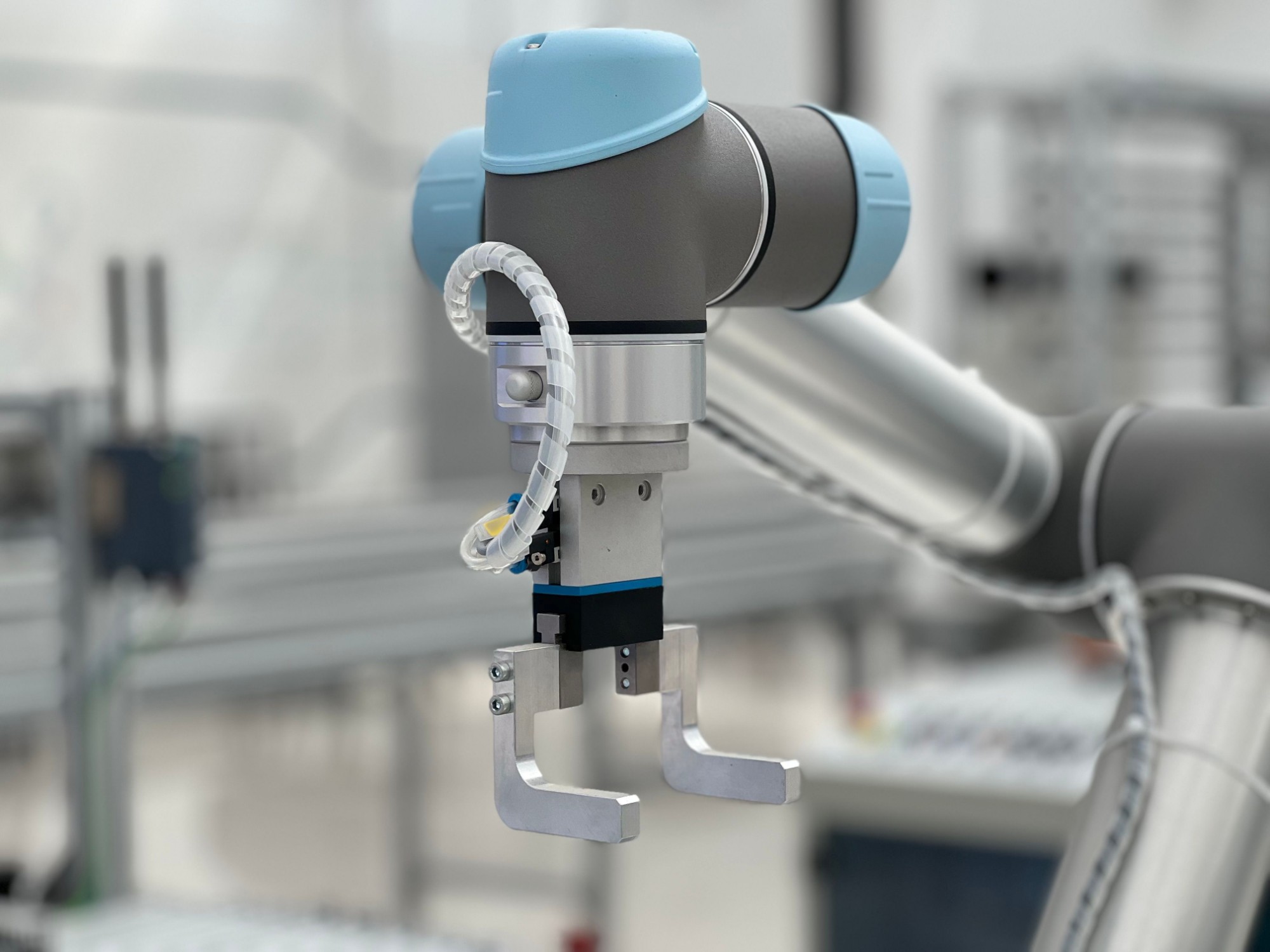 A collaborative robot arm with a gripper on a production line